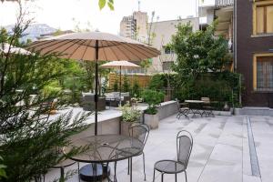 a patio with a table and chairs and an umbrella at BetweenLakes Studio ground floor west in Interlaken +3 photos