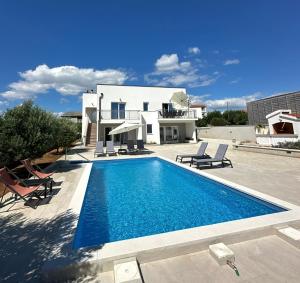 a villa with a swimming pool in front of a house at Villa Milutin 1 in Vrsi