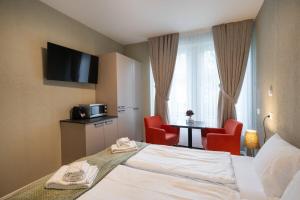 a hotel room with a bed and two red chairs at BetweenLakes Studio ground floor west in Interlaken