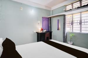a bedroom with a white bed and a purple door at Hotel O Sunrise Guest House in Guwahati