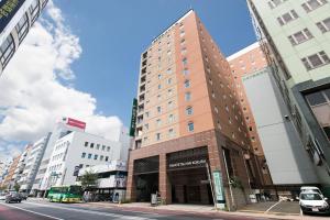um edifício alto ao lado de uma rua da cidade em Nishitetsu Inn Kokura em Kitakyushu