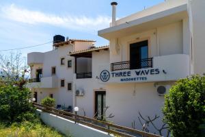 ミラトスにあるThree Waves Maisonettes Manoussosの3つの翼を持つ時計の看板が付いた白い建物