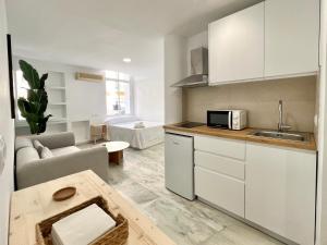 eine Küche mit weißen Schränken und ein Wohnzimmer in der Unterkunft La Plaza City Center & Beach Cozy Studios in Fuengirola