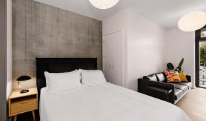 a bedroom with a white bed and a black chair at City Central Retreat - Sleek Studio Living in Wellington