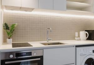 a kitchen with a sink and a washing machine at City Central Retreat - Sleek Studio Living in Wellington