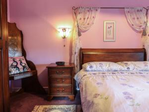 - une chambre avec un lit, une commode et une lampe dans l'établissement Hafoty Boeth Cottage, à Corwen