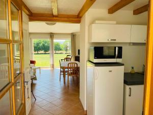 a kitchen with a refrigerator and a table with chairs at Gites le Fabras, espace de verdure, piscine collective et jeux in La Bâtie-Rolland