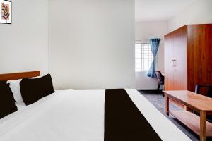 a bedroom with a large bed and a desk at Hotel O Sri Krishna Comforts in Bengaluru