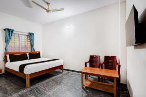 a bedroom with a bed and two chairs and a table at Hotel O Sri Krishna Comforts in Bengaluru