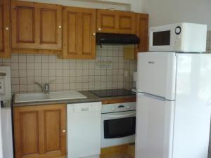 a kitchen with wooden cabinets and a white refrigerator at 2 pièces pour 4 pers, Sud-Est à Valloire, avec Wifi - FR-1-263-83 in Valloire +5 photos