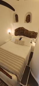 a white bed in a room with rocks on the wall at Aliori art caves in Aegiali