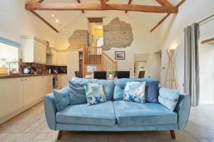 un divano blu in soggiorno con cucina di Beautiful Barn Conversion with Games Room a Ilfracombe Altre 14 foto