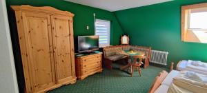 Un dormitorio con paredes verdes y un televisor y una mesa. en Landgasthaus Backhof-Helmle, en Breitnau