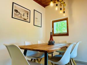 a dining room with a wooden table and white chairs at Bamboo Vendégház in Badacsonytördemic