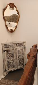 a mirror on a wall next to a wooden dresser at Aliori art caves in Aegiali