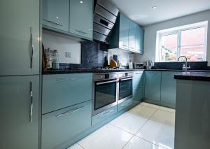 a kitchen with blue cabinets and a sink at Spacious 4BD Home with Patio garden, BBQ & Parking in Timsbury