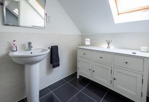 a white bathroom with a sink and a mirror at Spacious 4BD Home with Patio garden, BBQ & Parking in Timsbury +26 photos