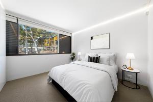 a white bedroom with a bed and a large window at Designer Darlinghurst Retreat Garage Parking in Sydney +8 photos