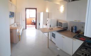 a kitchen with white cabinets and a table with a microwave at Meravisola Costa Rei Holiday Rooms in Castiadas