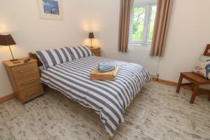 a bedroom with a bed with a blue and white striped blanket at Sea View Loft in Penzance
