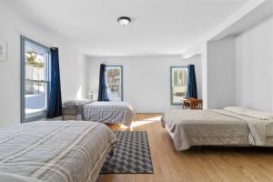 ein weißes Zimmer mit zwei Betten und zwei Fenstern in der Unterkunft Usine Stanstead in Beebe