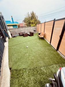 een kleine achtertuin met een gazon, stoelen en tafels bij Hostal Queltehue in Ancud