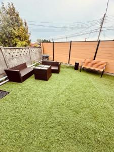 drie banken en een tafel in een tuin bij Hostal Queltehue in Ancud