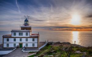 a lighthouse sitting on the edge of a body of water at Carnota PLAYA a 100 metros in Carnota