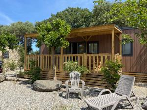 a small cabin with two chairs and a house at Location du Ranch Cantarettu in Algajola