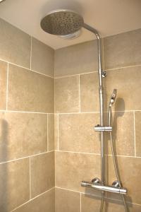 a shower with a shower head in a bathroom at Les appart'hotels de la fontaine in Autoire +92 photos