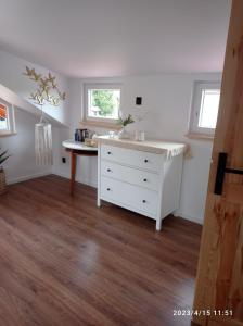 ein Zimmer mit einer weißen Kommode und einem Tisch in der Unterkunft Domek BOHO in Rydzewo