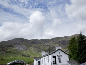 a white house with mountains in the background at YHA Coniston Coppermines in Coniston +8 photos