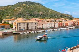 una barca che naviga lungo un fiume vicino a una città di Il Palazzo Storico a Bosa