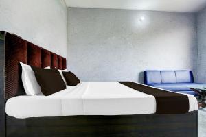 Un dormitorio con una cama grande y una silla azul. en Hotel O EB Hotel, en Amritsar