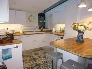 eine Küche mit weißen Schränken und einer Vase aus Blumen in der Unterkunft Wonderful Picturesque Countryside Cottage in Bloxham