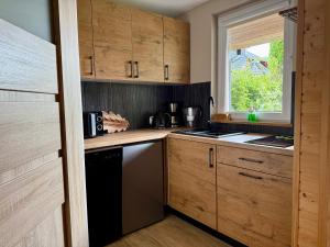 a kitchen with wooden cabinets and a black dishwasher at Domki Letniskowe Stokrotka in Pustkowo