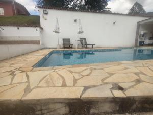 a swimming pool with two chairs next to a building at Chalé Arizona in São Roque