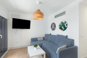 a living room with a blue couch and a tv at Flipper See View Maspalomas in Maspalomas
