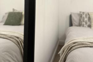 a mirror reflecting two beds in a bedroom at Cosy 1BD Getaway Perfect for Couples Stamford in Stamford