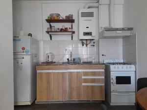 une cuisine avec des appareils électroménagers blancs et des armoires en bois dans l'établissement La Estrella - alojamiento temporario, à La Plata