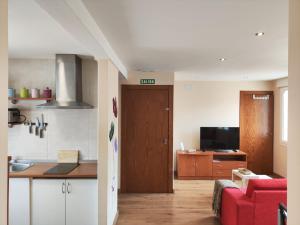 a kitchen and a living room with a red couch at El Sendero in Arguedas