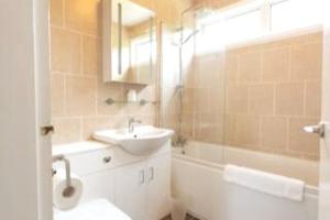 a bathroom with a sink and a toilet and a tub at Spacious Family Bungalow with Garden for up to 7 in Epsom
