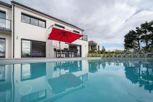 czerwony parasol w basenie z domem w obiekcie Villa avec piscine, vue mer, 200 m de la plage w mieście Clohars-Carnoët