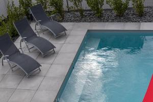 grupa krzeseł ustawionych obok basenu w obiekcie Villa avec piscine, vue mer, 200 m de la plage w mieście Clohars-Carnoët