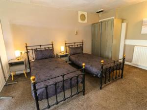 two beds in a room with two lamps and a cabinet at Newfield Apartment in Bishop Auckland