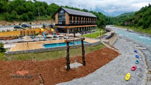 a building with a swimming pool next to a river at Valbona River Hotel in Jah Salih