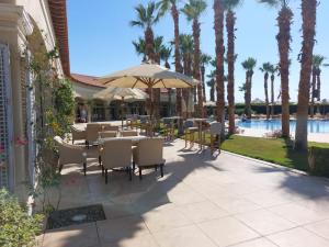 a patio with tables and chairs and a pool at Cozy, Calm, Studio in Veranda Sahl Hasheesh Resort in Hurghada