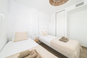 una camera da letto bianca con due letti e uno specchio di Boho Breeze Penthouse - By Oyoostays a Pilar de la Horadada Altre 32 foto