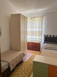 a bedroom with two beds and a cabinet and a window at Bosa appartamento Bouganville con vista mare ampio terrazzo in Magomadas