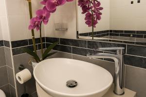 a bathroom with a sink and a mirror and purple flowers at NAPOLI VIBES Rooms in Naples